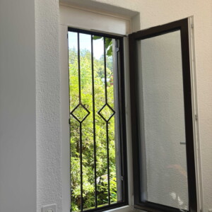 Fenstergitter mit Staketen und Karo-Ornamenten
